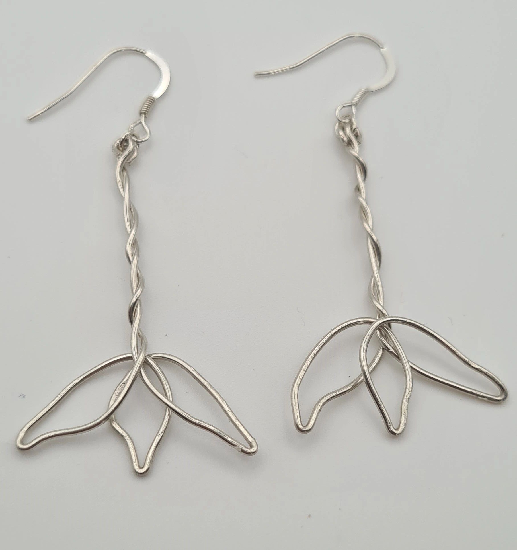 Close-up of handcrafted silver flower wire earrings.